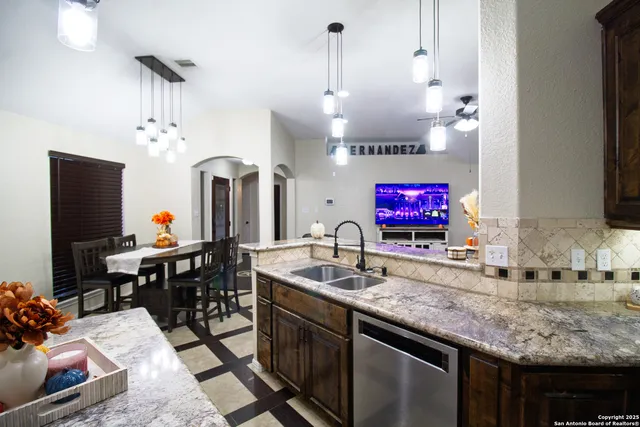 a living room with kitchen island furniture a chandelier and a flat screen tv