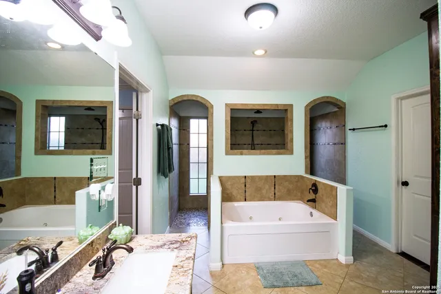 a bathroom with a tub sink and mirror
