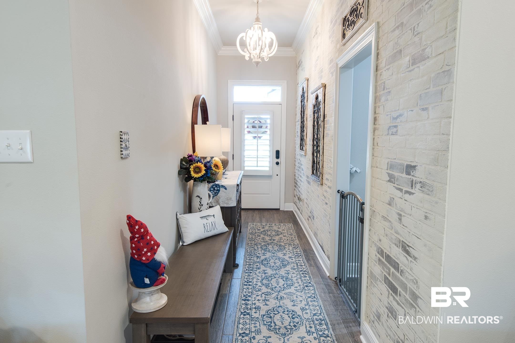 9988 Dunleith Loop Daphne, AL 36526 - Photo 25 of 51 Doorway to outside with a notable chandelier, ornamental molding, dark hardwood / wood-style floors, and brick wall