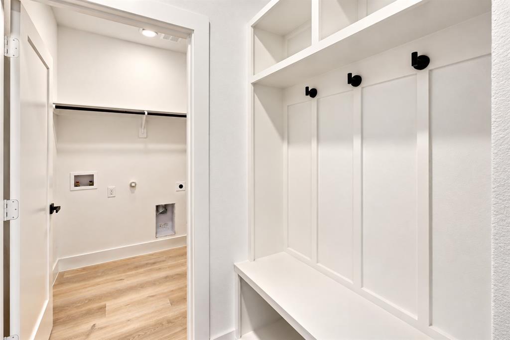 1640 West Wintergreen Road Lancaster, TX 75134 - Photo 28 of 37 Built-in storage bench with upper shelving, coat hooks, and a laundry room with wood-finish flooring
