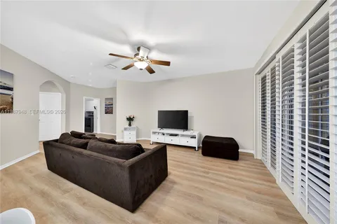 a view of a dining room and livingroom with furniture wooden floor a rug a painting and a chandelier