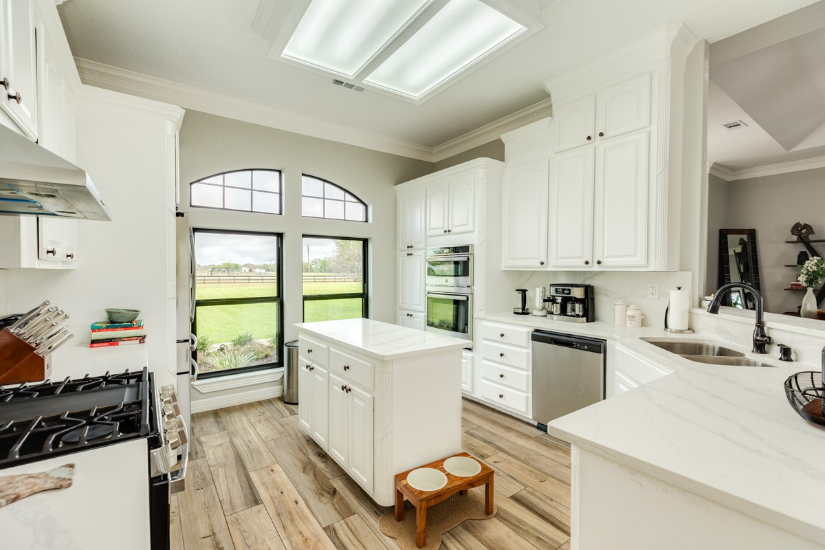 20111 Farm To Market Road 523 Angleton, TX 77515 - Photo 35 of 47 a large white kitchen with a stove a sink dishwasher and white cabinets with wooden floor