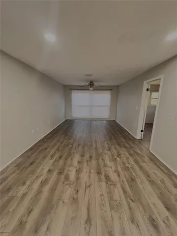 an empty room with wooden floor and ceiling fan