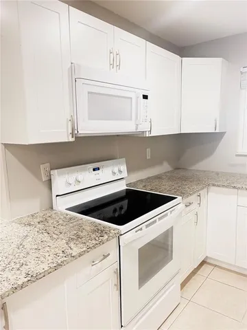 a kitchen with granite countertop white cabinets and white appliances