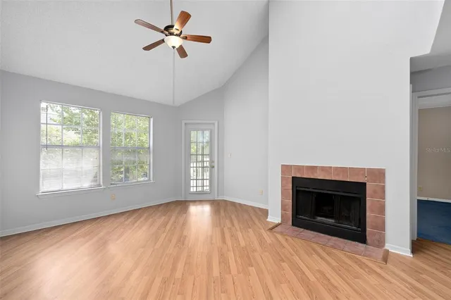 a view of empty room with a fireplace wooden floor and fan