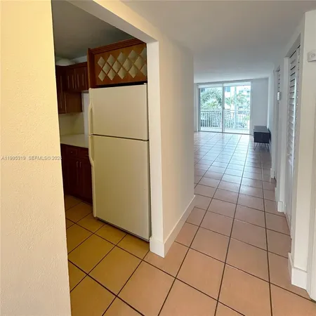 a view of a refrigerator in kitchen and an empty room