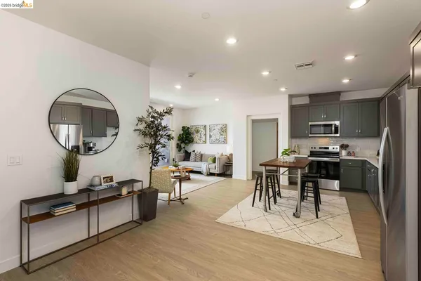 a living room with furniture a mirror kitchen view and a wooden floor