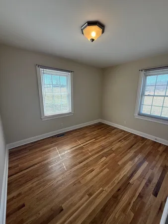an empty room with windows and wooden floor