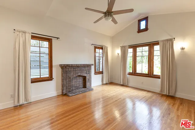 a view of an empty room with window and wooden floor