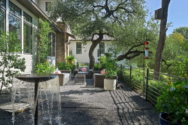 a view of a patio with table and chairs potted plants and large tree