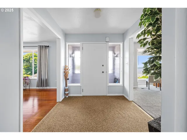 a view of an empty room with window and hardwood floor