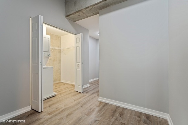 235 West Van Buren Street, Unit 1505 Chicago, IL 60607 - Photo 8 of 28 a view of an empty room with wooden floor and a window