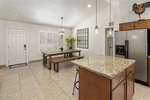a kitchen with granite countertop a table chairs and refrigerator