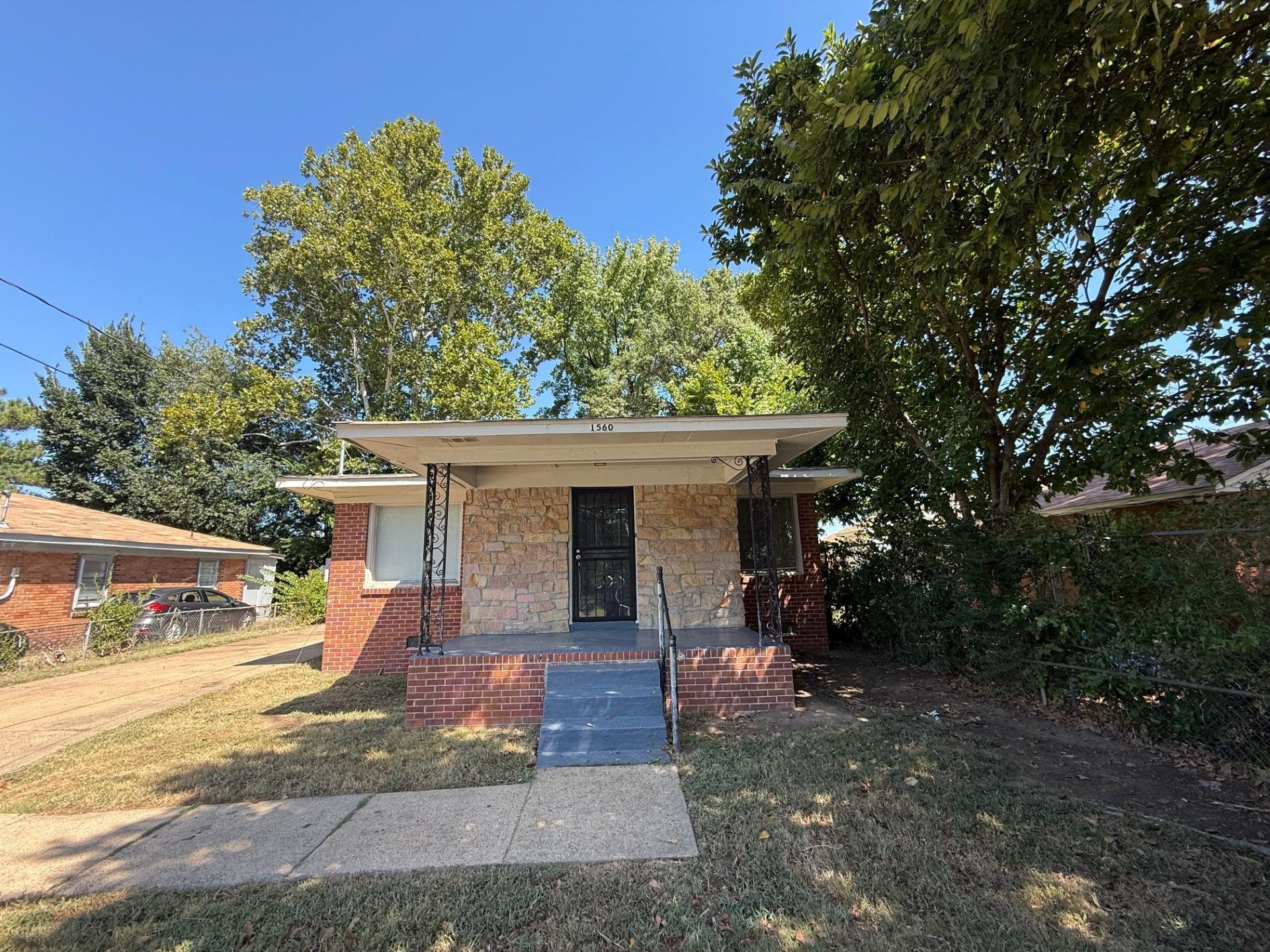 Bungalow featuring a porch, stone siding, and a front lawn