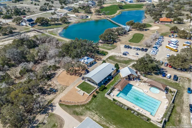 an aerial view of a residential houses with outdoor space and trees all around