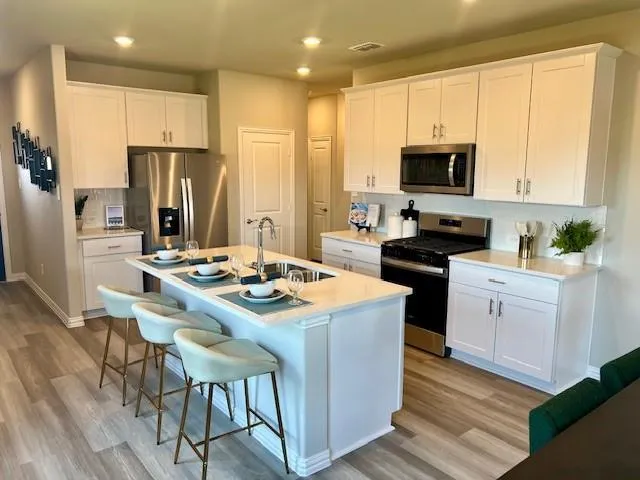 a kitchen that has a lot of white cabinets and stainless steel appliances