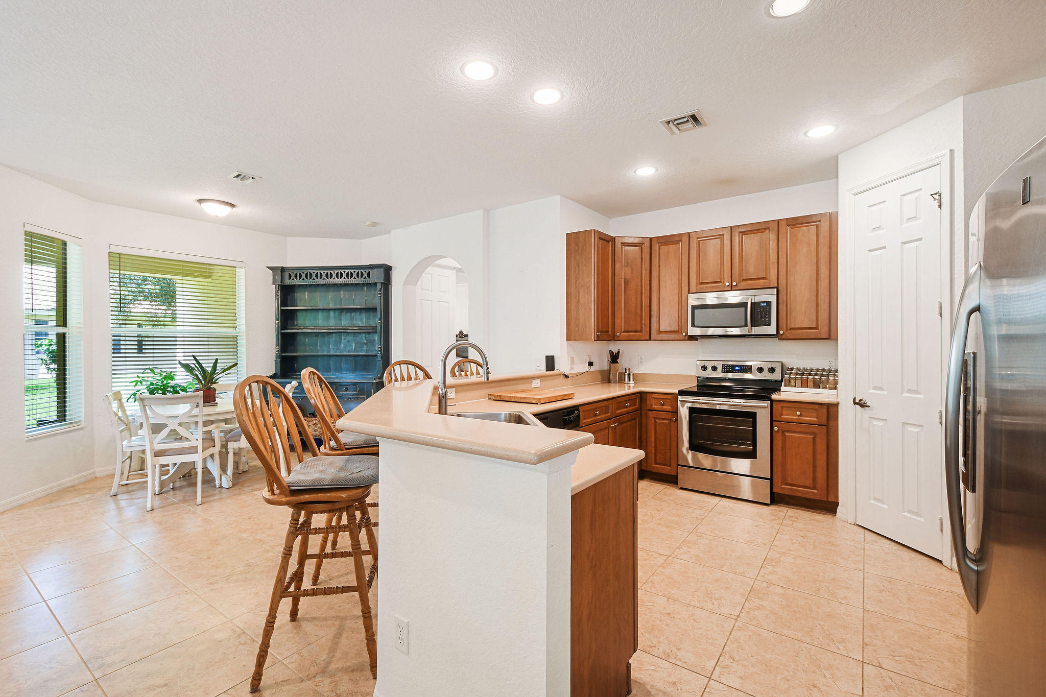 4100 Silverstone Drive Fort Pierce, FL 34947 - Photo 18 of 42 a kitchen with stainless steel appliances granite countertop a stove top oven a sink dishwasher a dining table and chairs with wooden floor