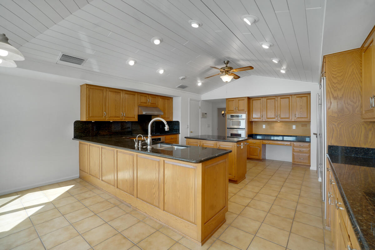 19842 Wilkinson Leas Road Jupiter, FL 33469 - Photo 30 of 75 a large kitchen with stainless steel appliances a large counter top a stove and a sink