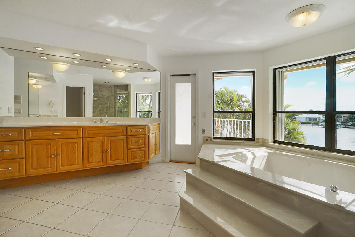 19842 Wilkinson Leas Road Jupiter, FL 33469 - Photo 35 of 75 a spacious bathroom with a double vanity sink a large mirror and a bathtub with shower