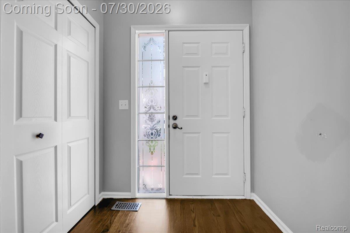 Entryway featuring a paneled door with decorative sidelight, wood-finish flooring, and a bifold closet