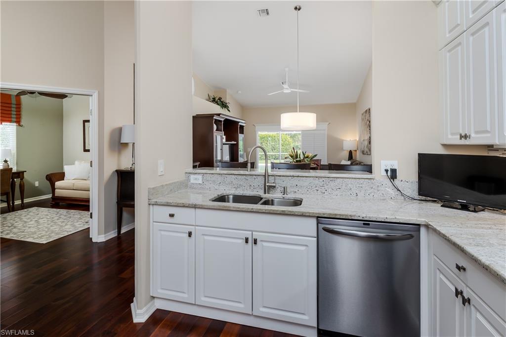 6658 Castlelawn Place, Unit 9 Naples, FL 34113 - Photo 7 of 38 Kitchen featuring a breakfast bar with stone countertop, white shaker cabinetry, stainless steel appliances, and a tiled backsplash