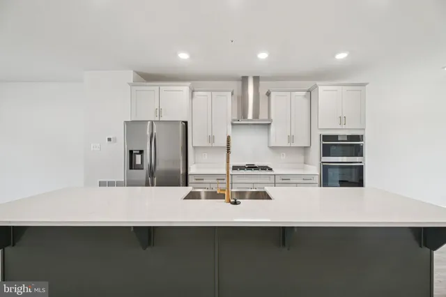 a kitchen with kitchen island a sink stainless steel appliances and white cabinets