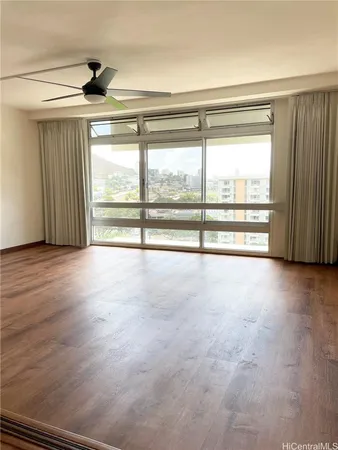 a view of empty room with wooden floor and fan