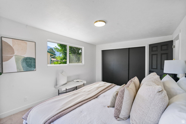432 Calnette Drive Sandy, UT 84070 - Photo 16 of 48 Bedroom featuring a window with exterior scenery, a flush-mount ceiling light, white walls, and light-toned carpet flooring