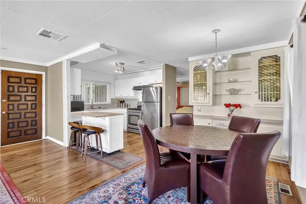 a dining room with wooden floor a chandelier a wooden table and chairs
