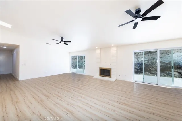 an empty room with wooden floor fan and windows