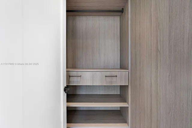 a spacious bedroom with a large window and a chandelier