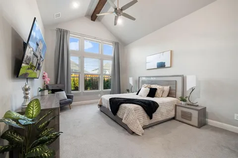 a bedroom with a bed couch and large windows