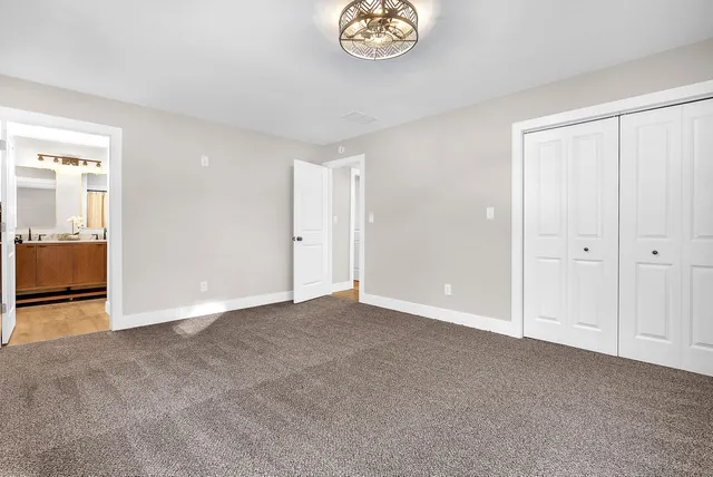 an empty room with chandelier fan and windows