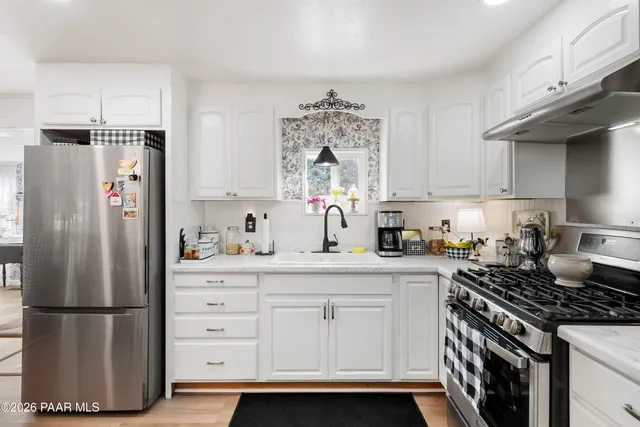 a kitchen with a refrigerator a stove a sink and white cabinets