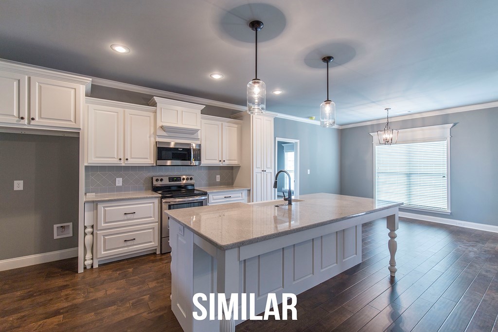 103 Timber Ridge Circle, Unit 139 Byron, GA 31008 - Photo 6 of 30 a large kitchen with kitchen island a stove a sink a center island and wooden floor