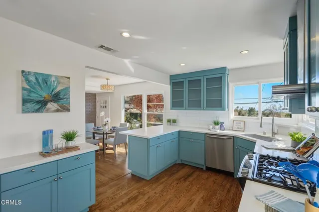a kitchen with stainless steel appliances granite countertop a sink and wooden floors