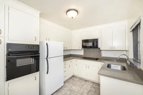 a kitchen with granite countertop a sink stove and refrigerator