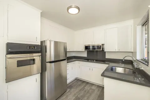a kitchen with granite countertop a sink stove and refrigerator