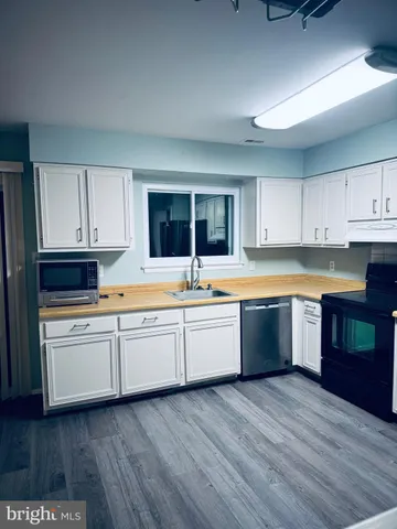 a kitchen with wooden floors and white cabinets