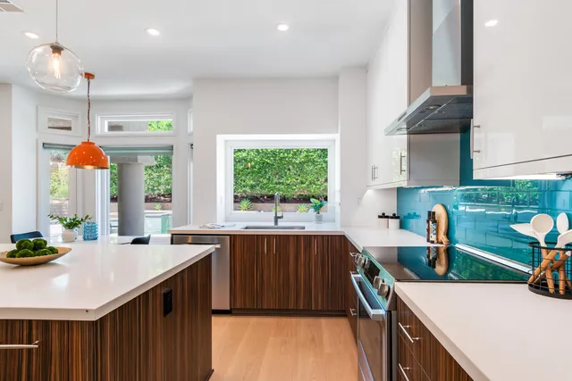 a kitchen that has a lot of white cabinets and stainless steel appliances