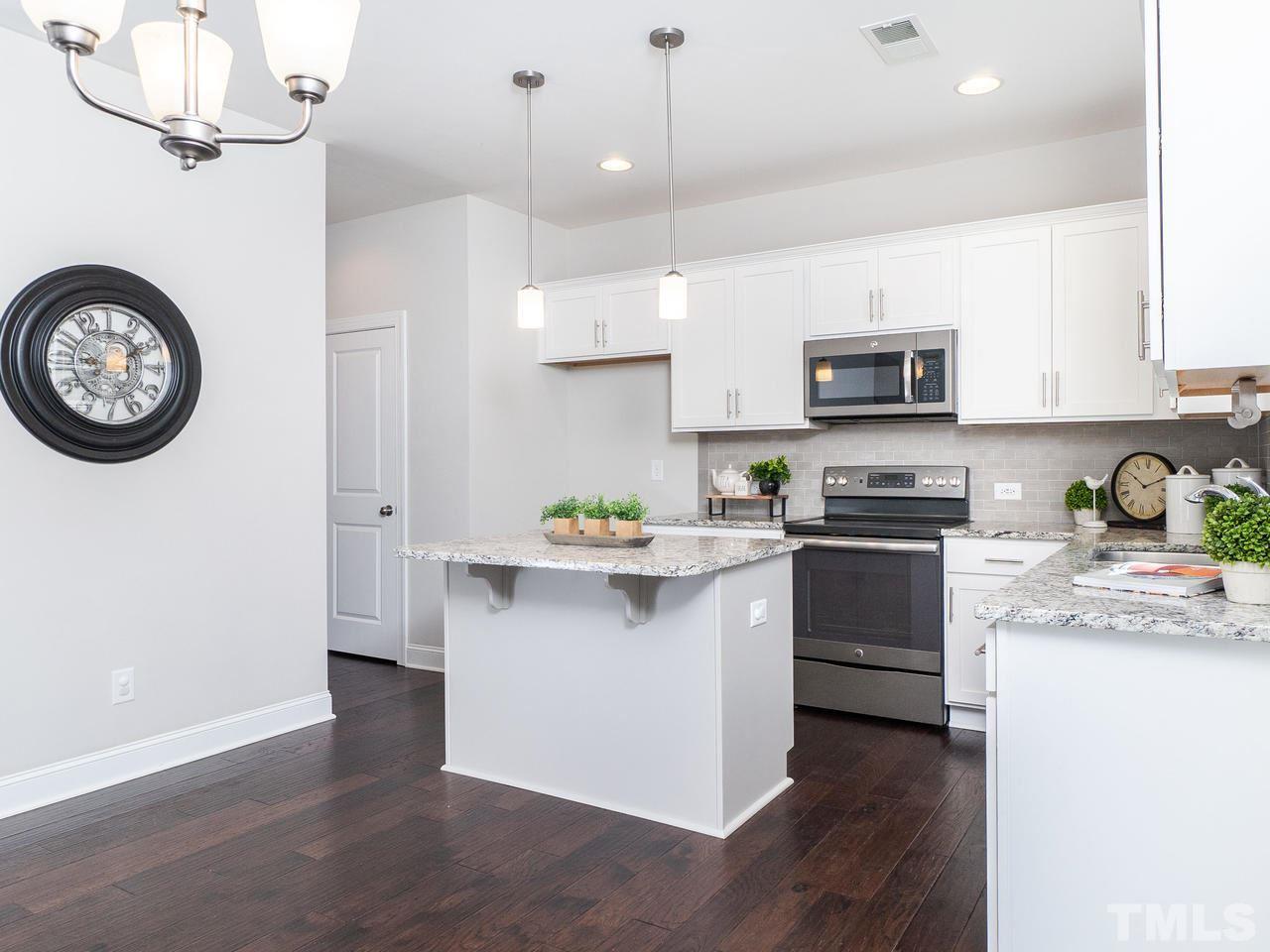 1132 Silver Farm Road Raleigh, NC 27603 - Photo 2 of 11 a kitchen with kitchen island granite countertop a stove a sink and a clock
