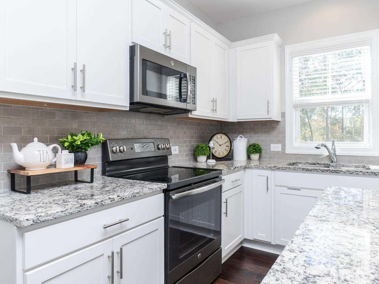 1132 Silver Farm Road Raleigh, NC 27603 - Photo 3 of 11 a kitchen with granite countertop white cabinets white appliances a potted plant and a window