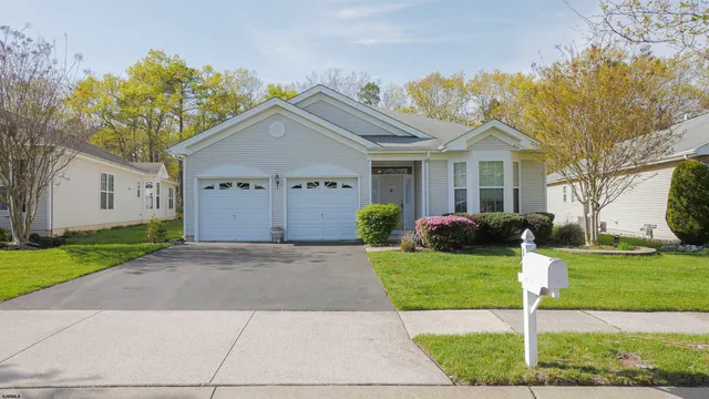 a front view of a house with a garden and trees