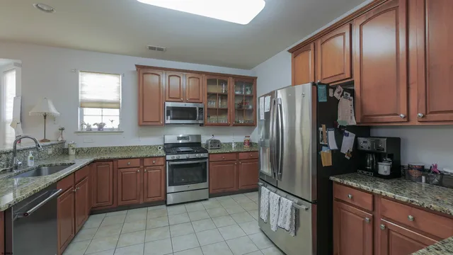 a kitchen with stainless steel appliances granite countertop a refrigerator stove sink and cabinets