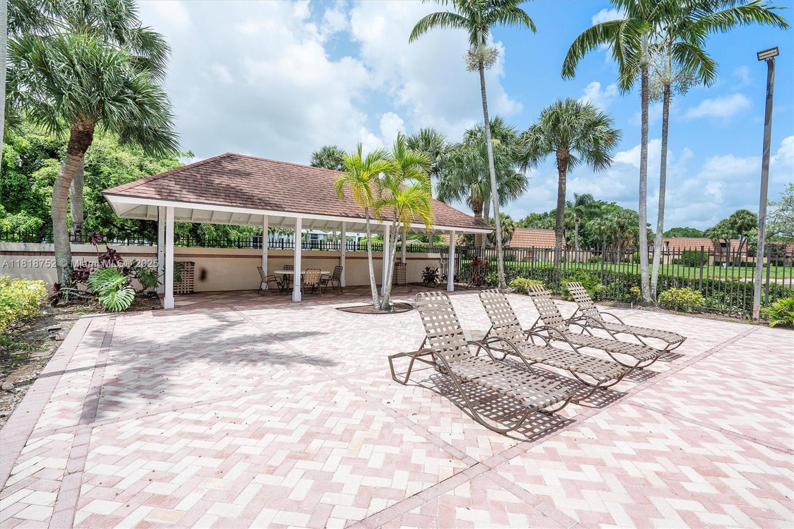 839 Blue Ridge Circle, Unit 839 West Palm Beach, FL 33409 - Photo 26 of 34 a view of a backyard with a patio table and chairs under an umbrella