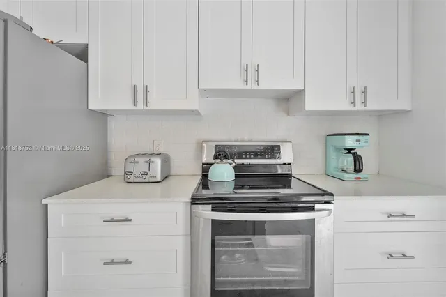 a kitchen with white cabinets and appliances