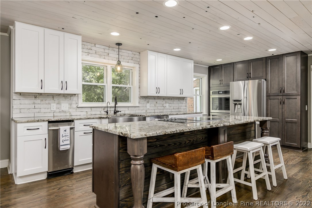 190 Valhalla Road Southern Pines, NC 28387 - Photo 12 of 39 a kitchen with stainless steel appliances granite countertop a stove a sink a microwave a refrigerator and white cabinets