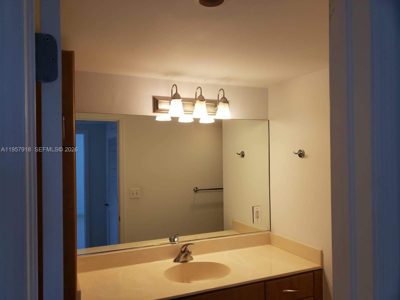 401 69th Street, Unit 906 Miami Beach, FL 33141 - Photo 21 of 24 a bathroom with a sink and a mirror