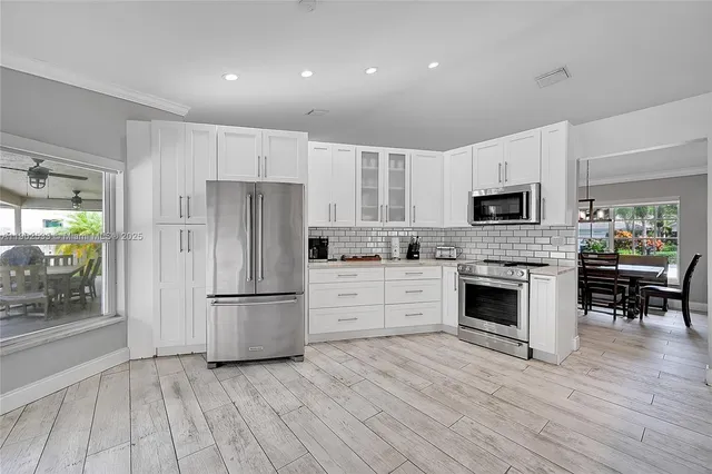 a kitchen with white cabinets and stainless steel appliances
