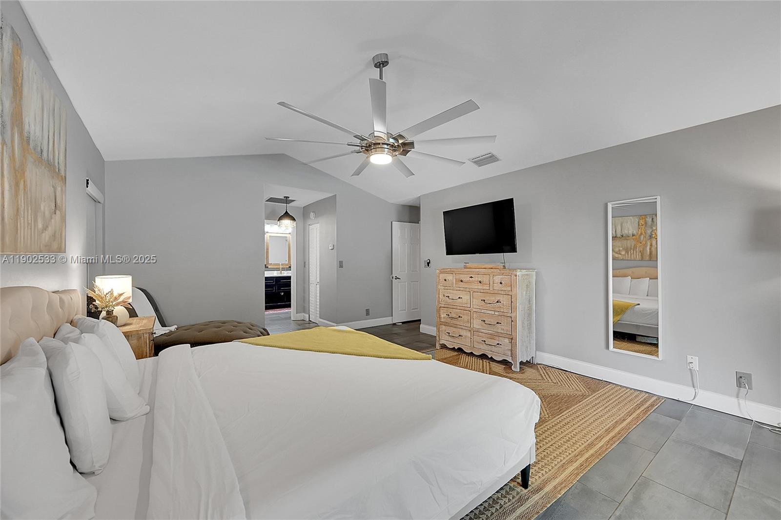 9841 Southwest 1st Street, Unit 9841 Plantation, FL 33324 - Photo 29 of 37 a bedroom with a bed a chandelier and a flat screen tv